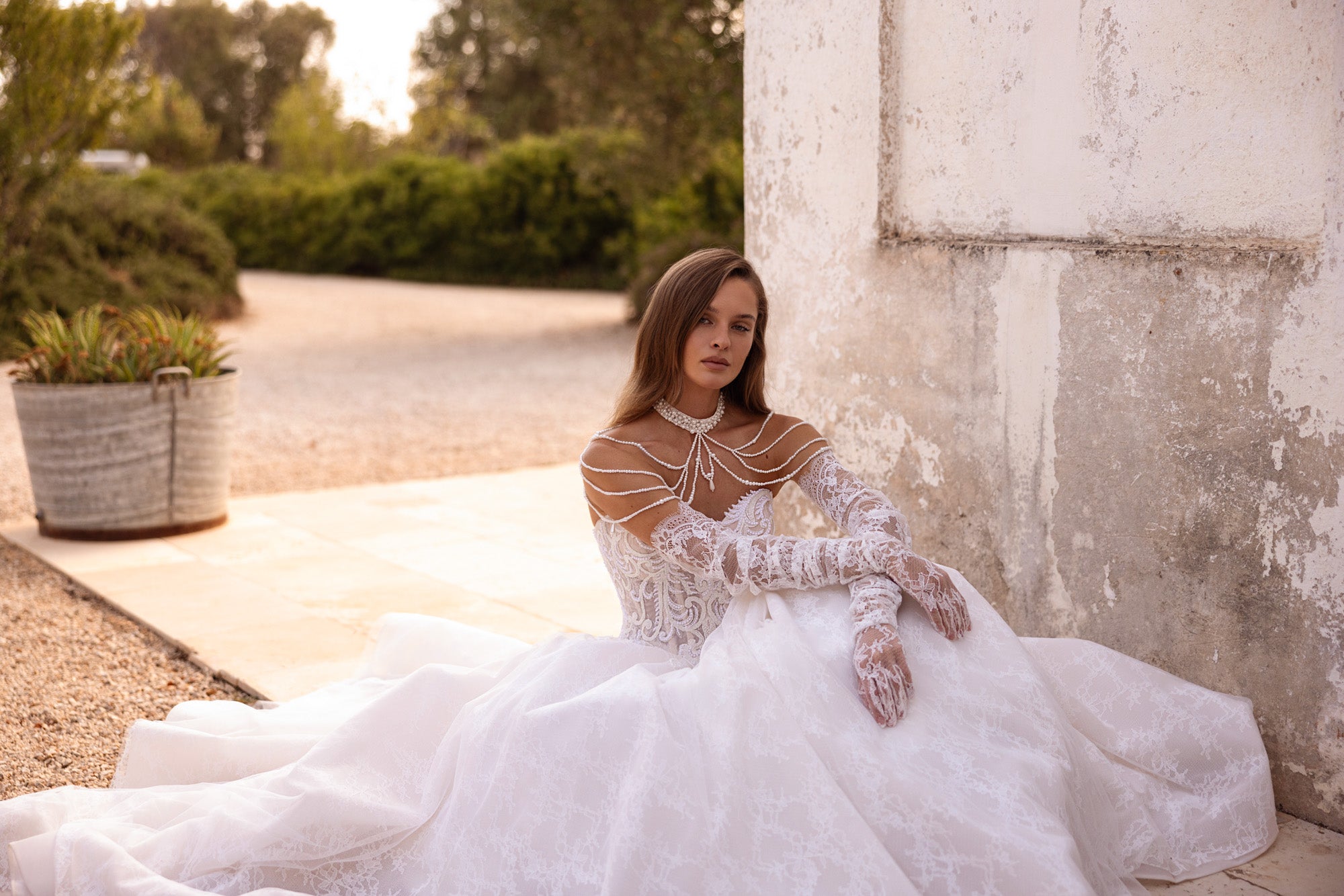Ivory wedding dress featuring a full tulle skirt, long lace sleeves, and layered pearl shoulder details