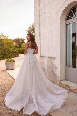 Back view of an ivory ball gown wedding dress with pearl shoulder drapes, lace detailing, and a long train