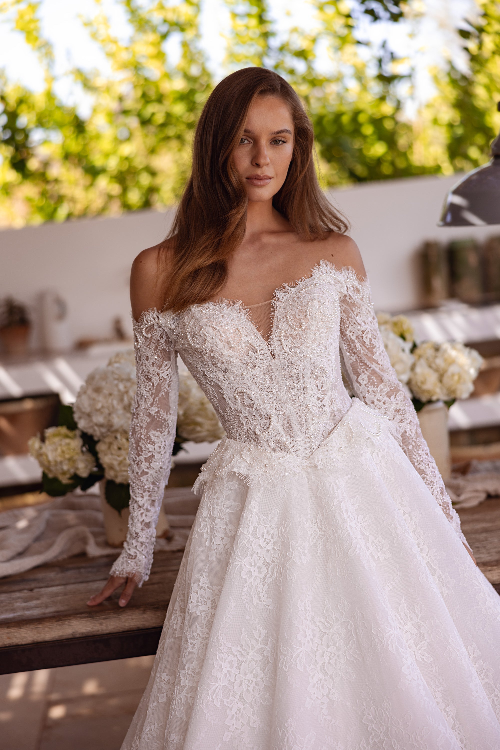 Intricate lace bodice and off-the-shoulder long sleeves on an ivory wedding dress