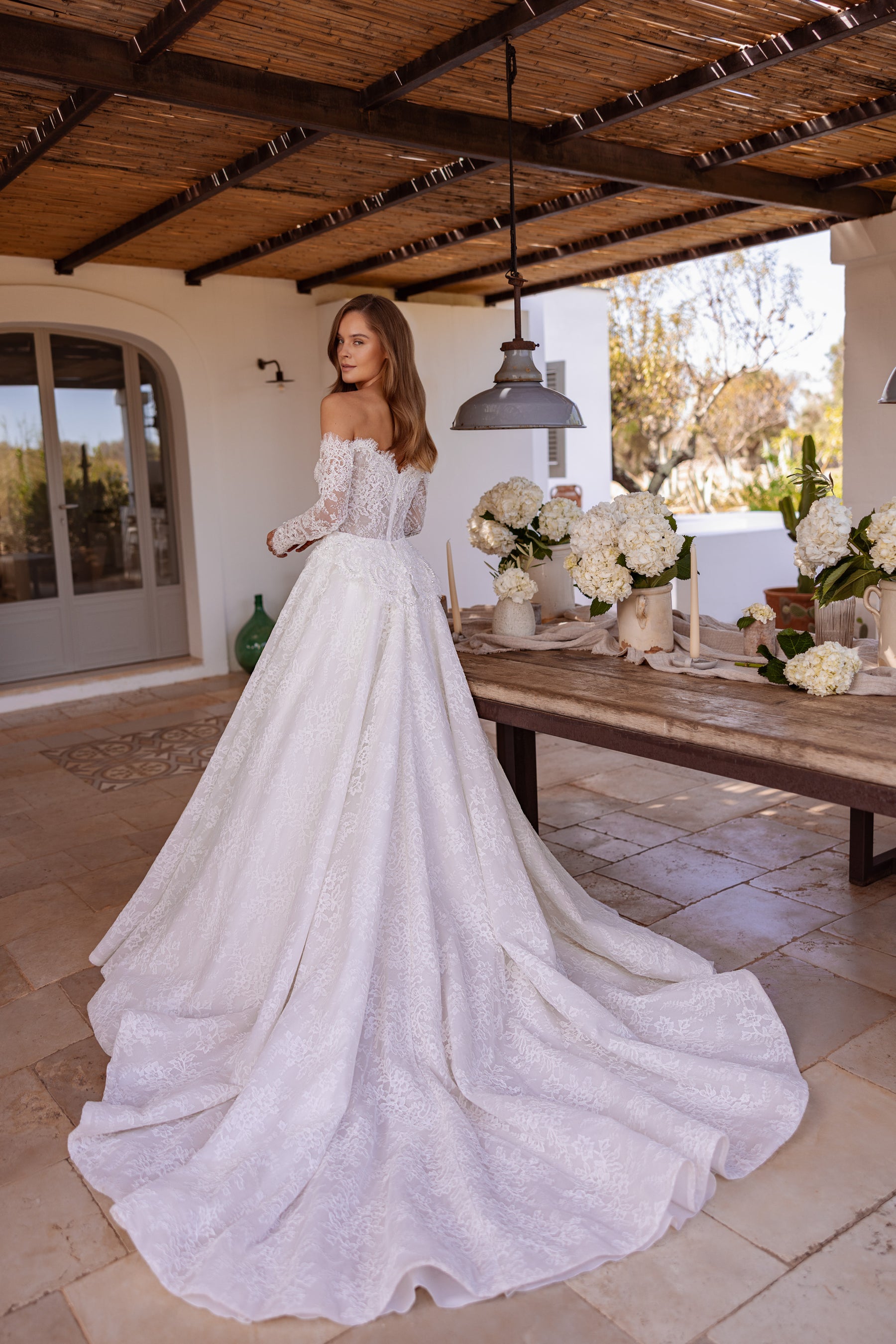 Lace-backed ivory wedding dress with long sleeves, a full A-line skirt, and an extended train
