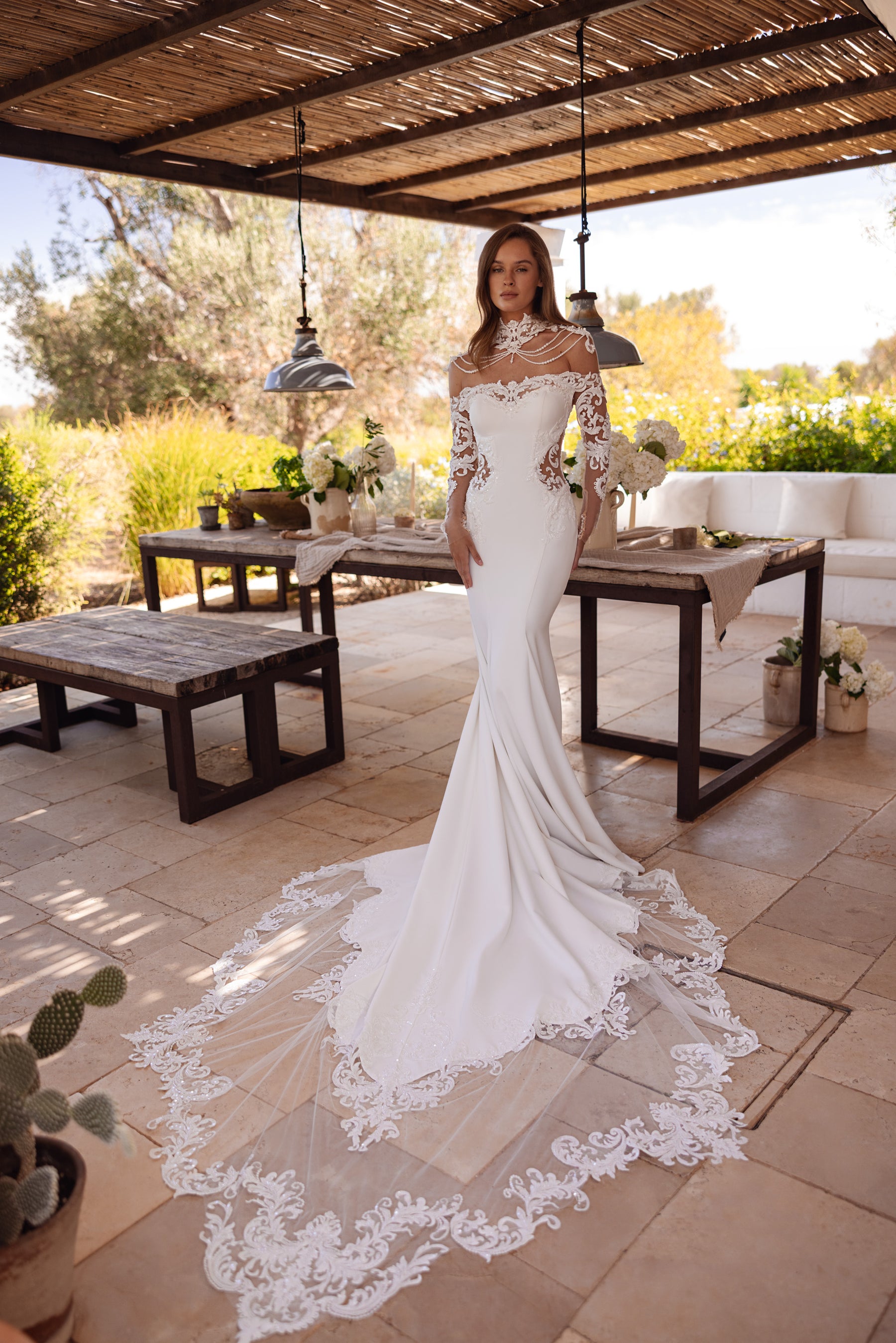 Ivory mermaid wedding dress with sheer lace sleeves, beaded neckline, and a long floral lace-edged train