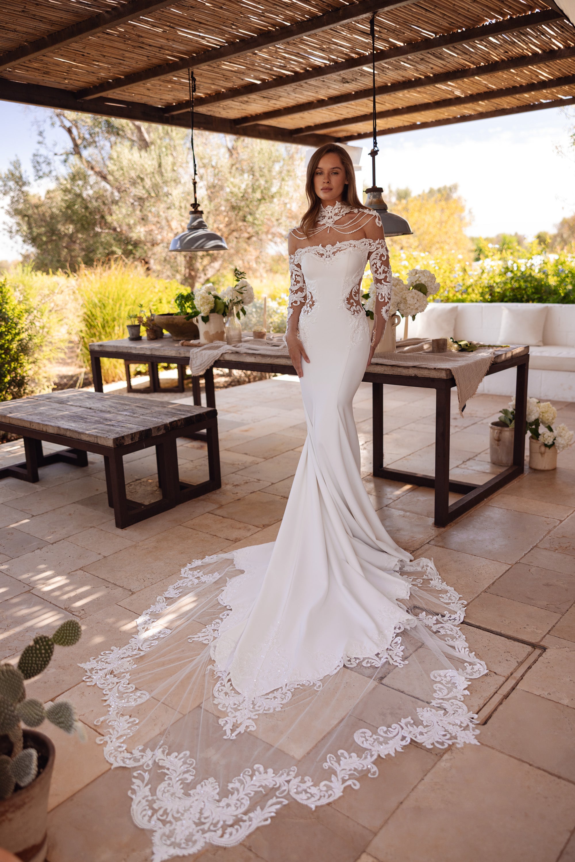 Ivory mermaid wedding dress with sheer lace sleeves, beaded neckline, and a long floral lace-edged train
