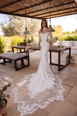 Ivory mermaid wedding dress with sheer lace sleeves, beaded neckline, and a long floral lace-edged train