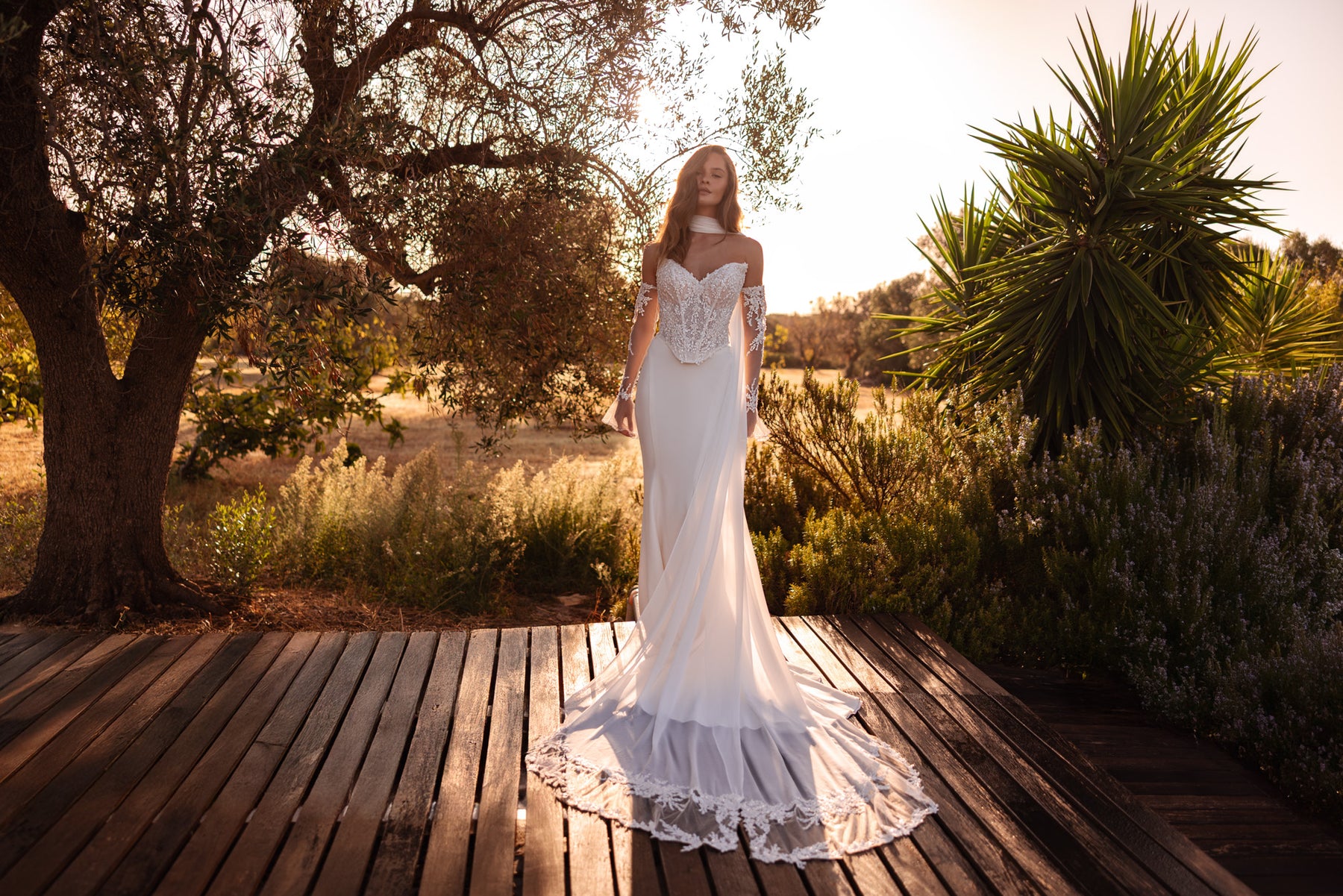 Ivory mermaid wedding dress with a sparkling lace bodice, sheer long sleeves, and a lace-trimmed train