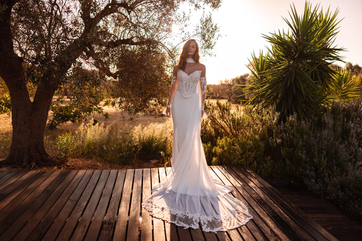 Ivory mermaid wedding dress with a sparkling lace bodice, sheer long sleeves, and a lace-trimmed train