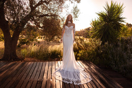 Ivory mermaid wedding dress with a sparkling lace bodice, sheer long sleeves, and a lace-trimmed train