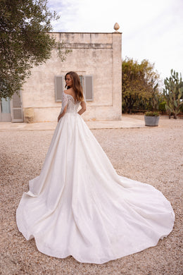 Ivory ball gown wedding dress with a wide flowing skirt, shimmering embroidery, and an extended train