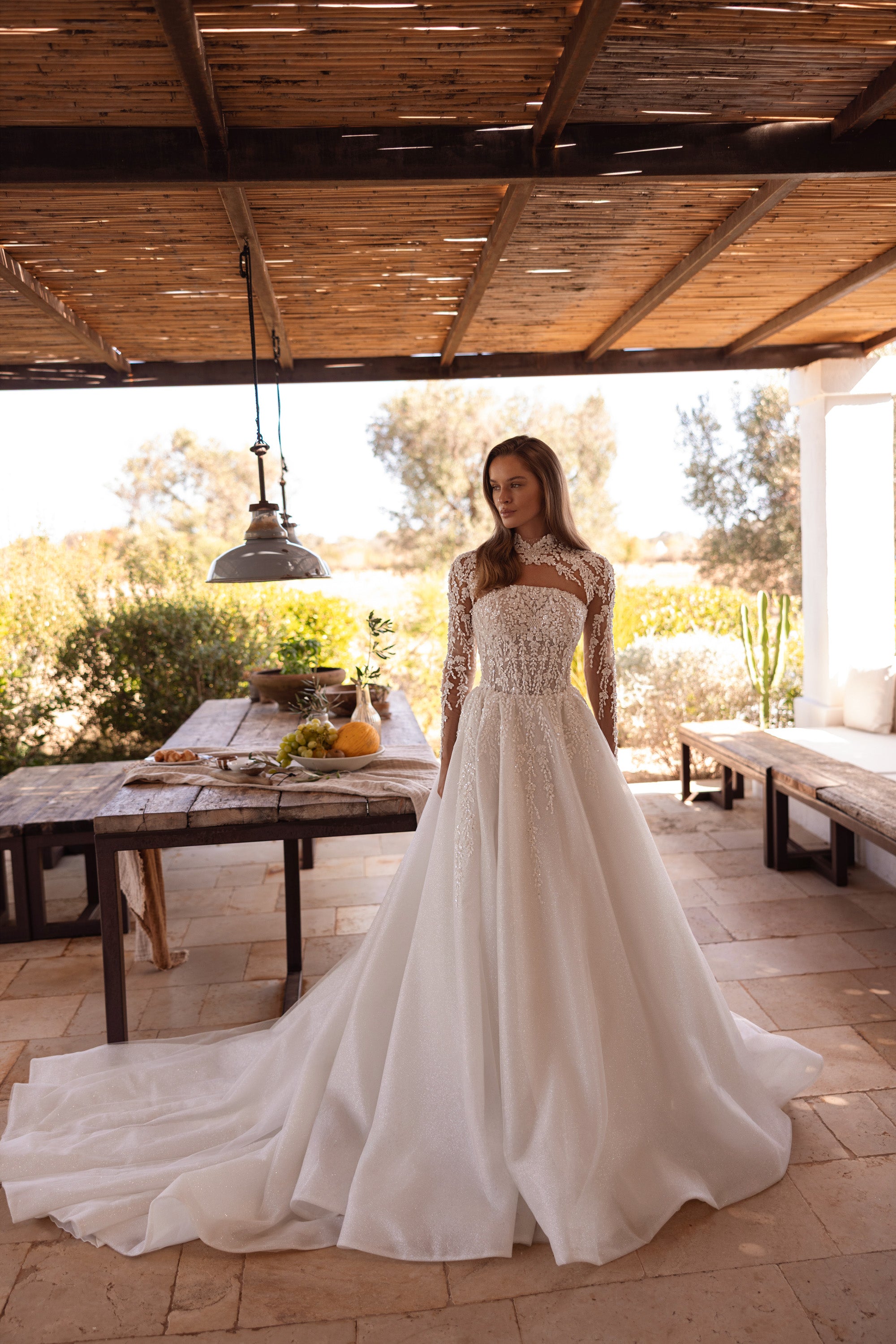 Glittering ivory A-line wedding dress with a sheer high neckline, long lace sleeves, and a sweeping train