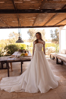 Glittering ivory A-line wedding dress with a sheer high neckline, long lace sleeves, and a sweeping train