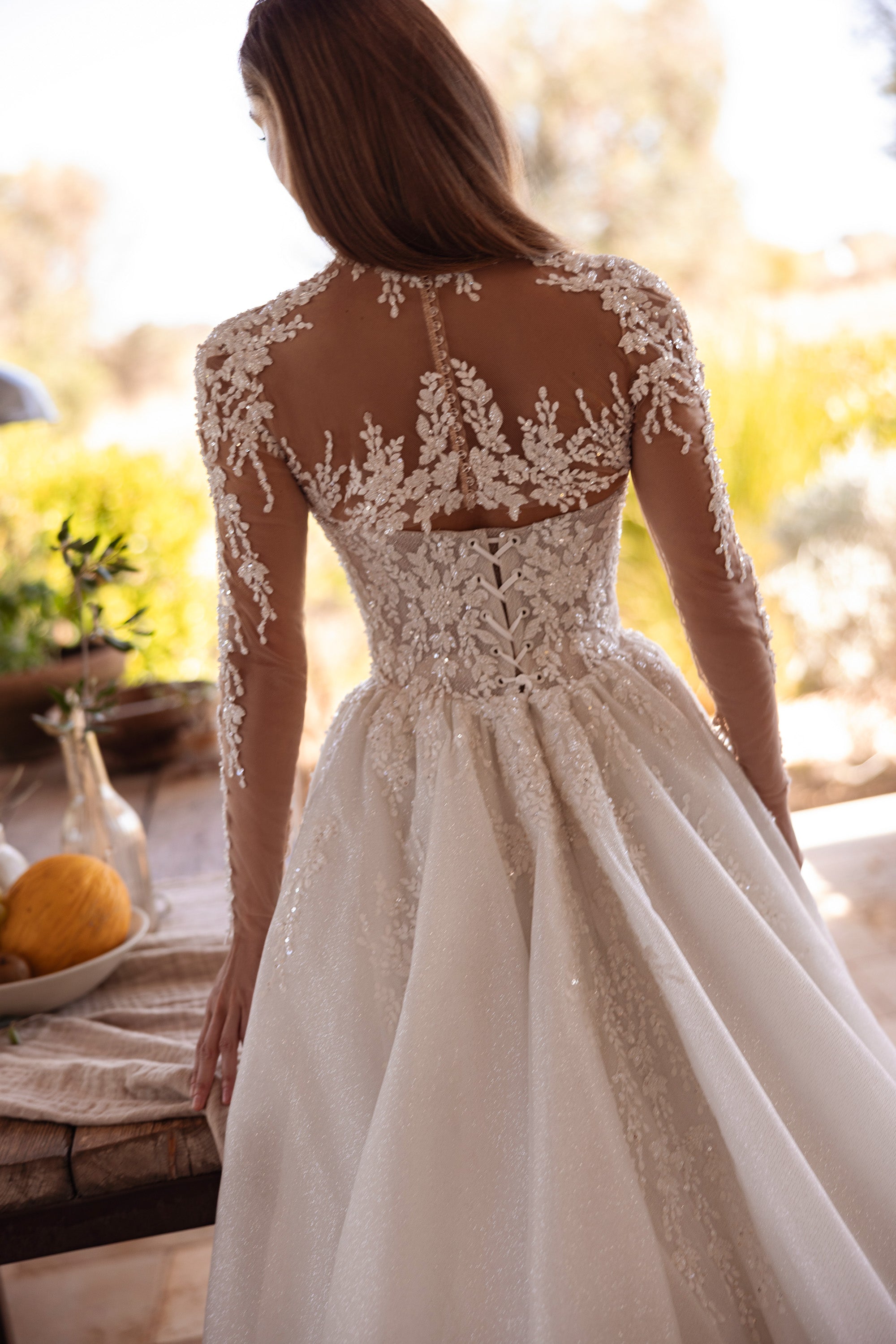 Sheer floral-lace back and long sleeves detail on an ivory wedding dress with a full flowing skirt
