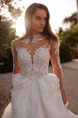 Close-up of an ivory wedding dress with sheer long sleeves, floral lace appliqués, and a beaded high neckline