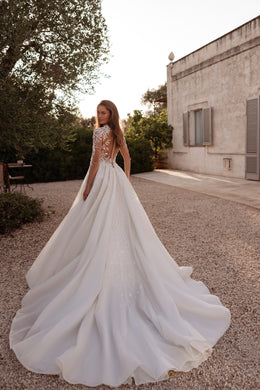 Ivory wedding dress with a sheer lace back, full A-line skirt, and sweeping layered train