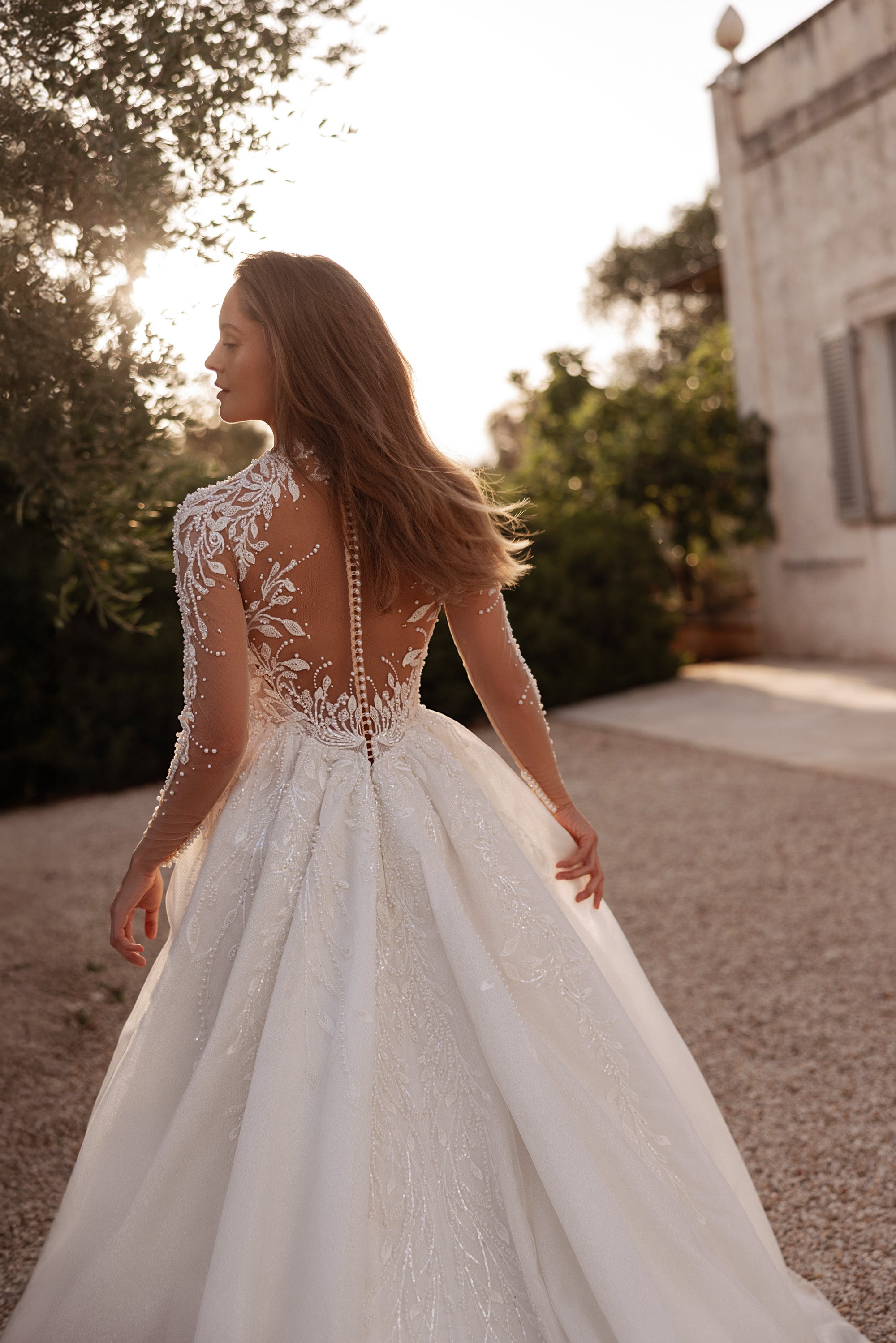 Sheer lace back with covered buttons and long sleeves on an ivory wedding dress with a full skirt