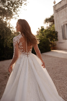 Sheer lace back with covered buttons and long sleeves on an ivory wedding dress with a full skirt