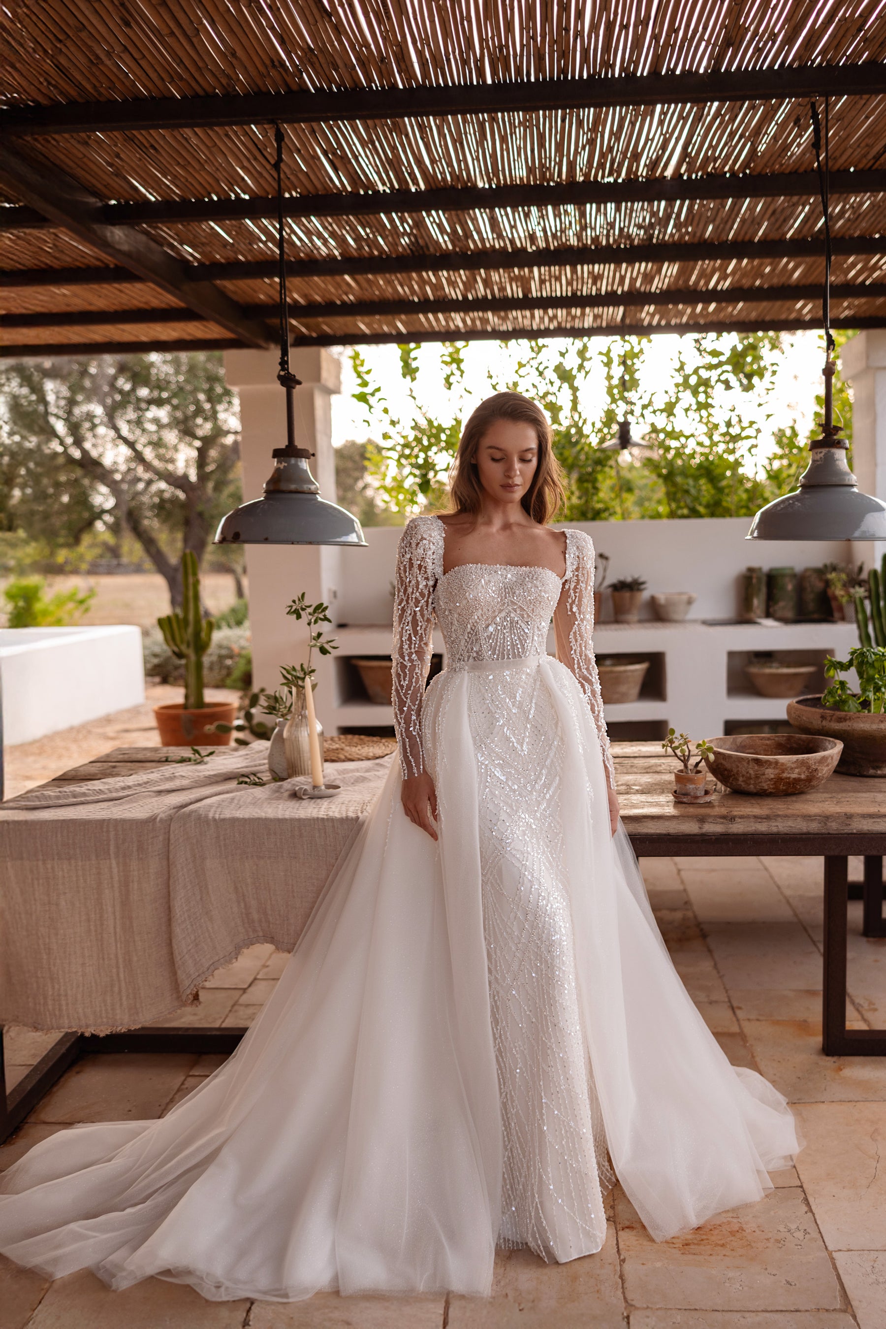 Ivory beaded sheath wedding dress shown with a detachable tulle overskirt spreading into a long train