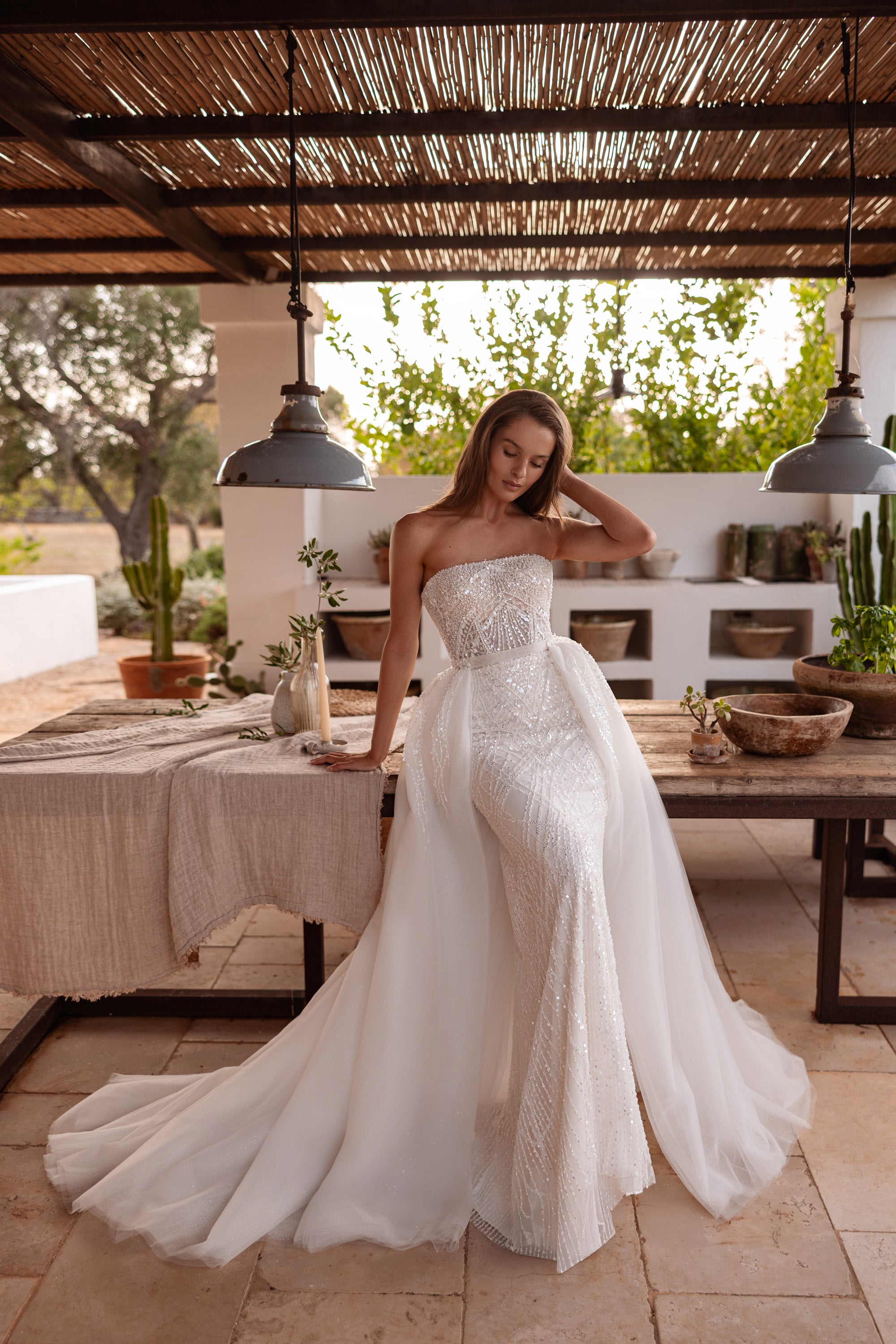 Strapless beaded sheath wedding dress paired with a flowing tulle overskirt and sweeping train