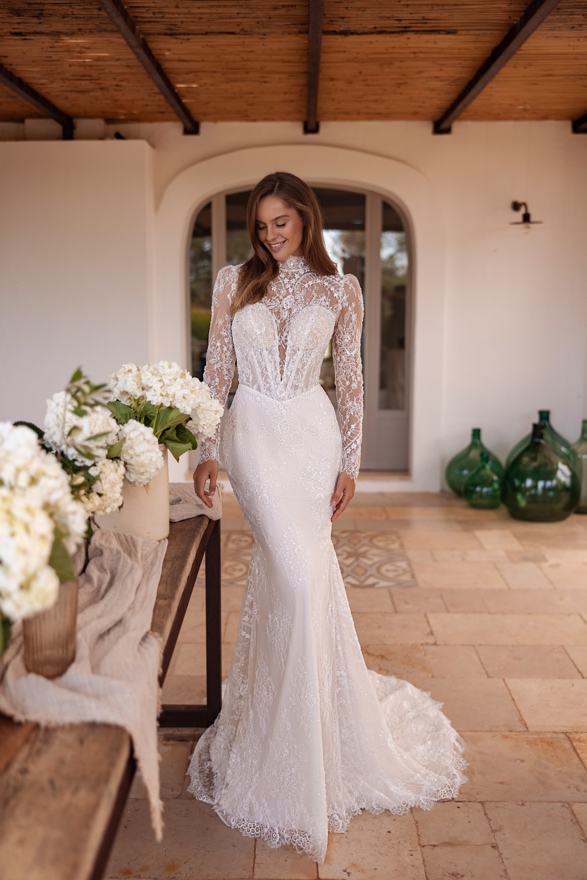 Ivory fitted wedding dress with a high illusion neckline, sheer floral lace sleeves, and a lace train