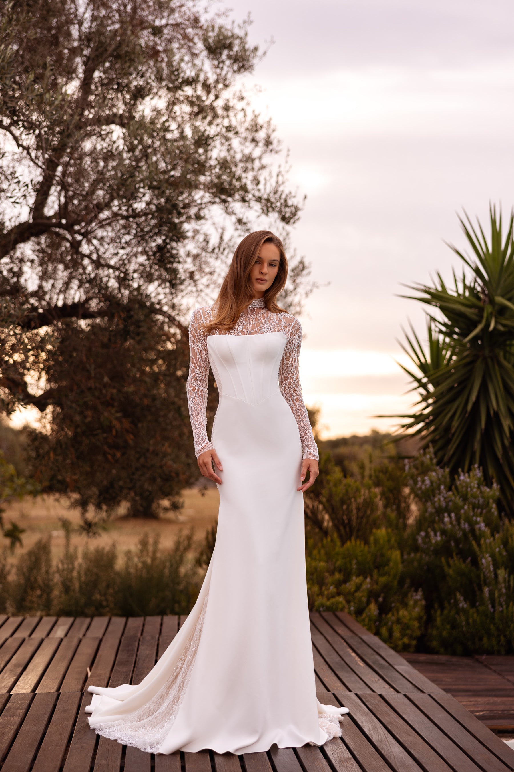 Fitted ivory wedding dress with sheer floral lace sleeves, a square neckline, and a sweeping train