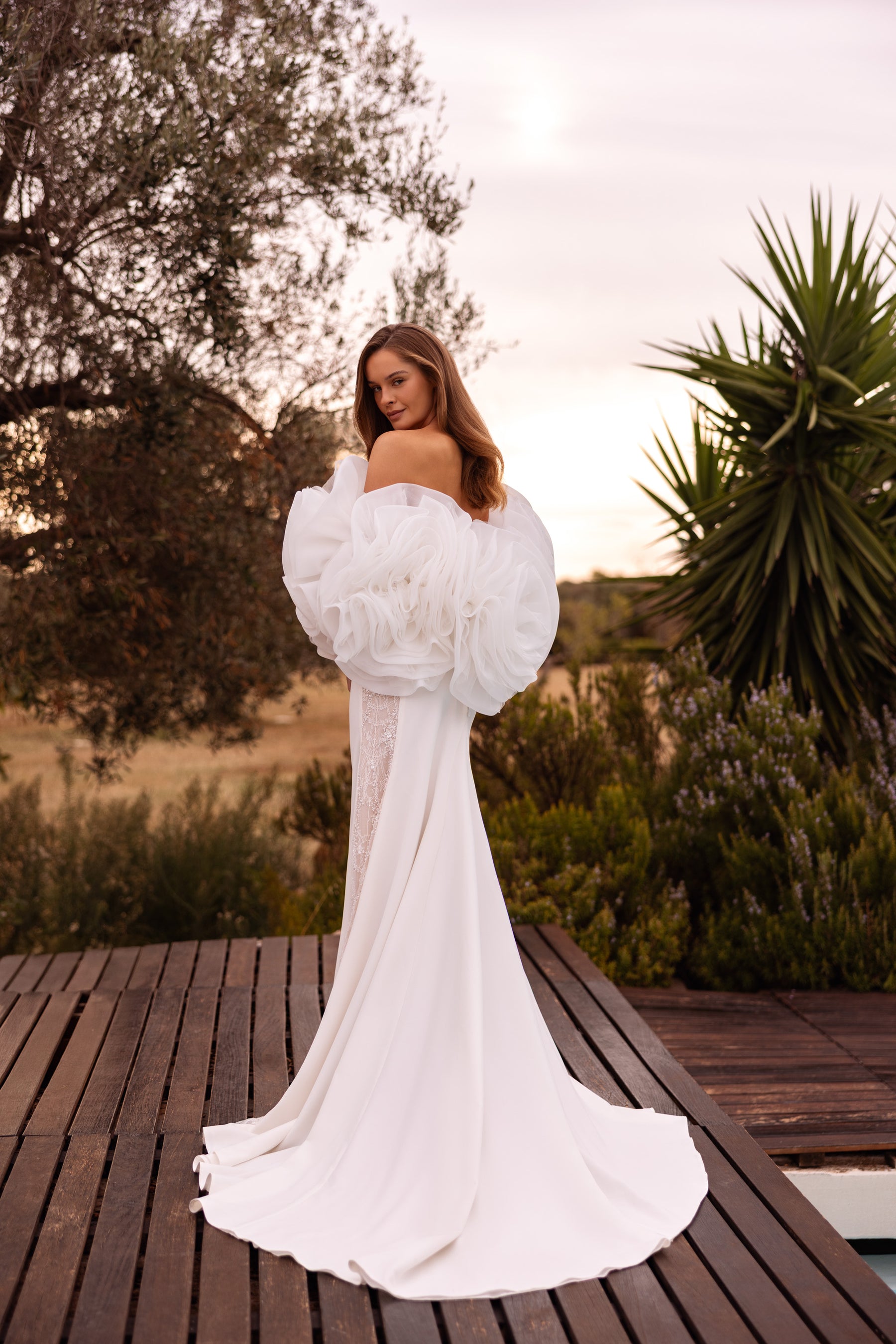 Ivory sheath wedding dress with voluminous floral puff sleeves, lace side panels, and a long train