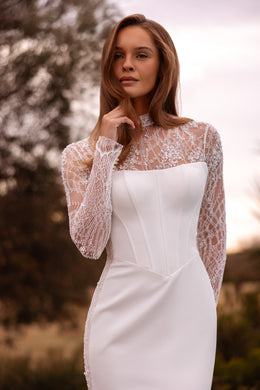 Close-up of an ivory wedding dress with sheer floral lace sleeves and a structured square-neck bodice