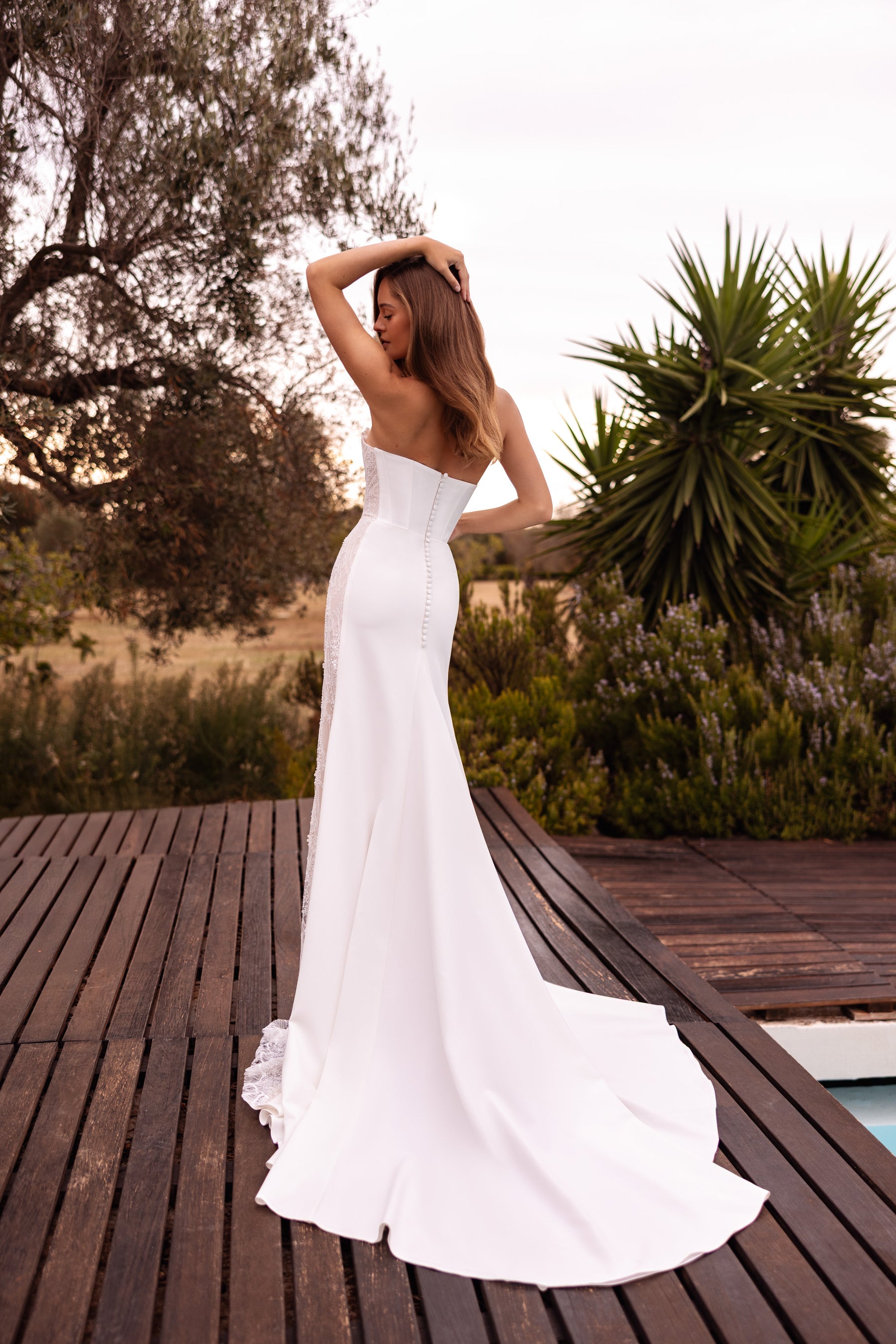 Strapless ivory sheath wedding dress shown from the back with a smooth silhouette and sweeping train
