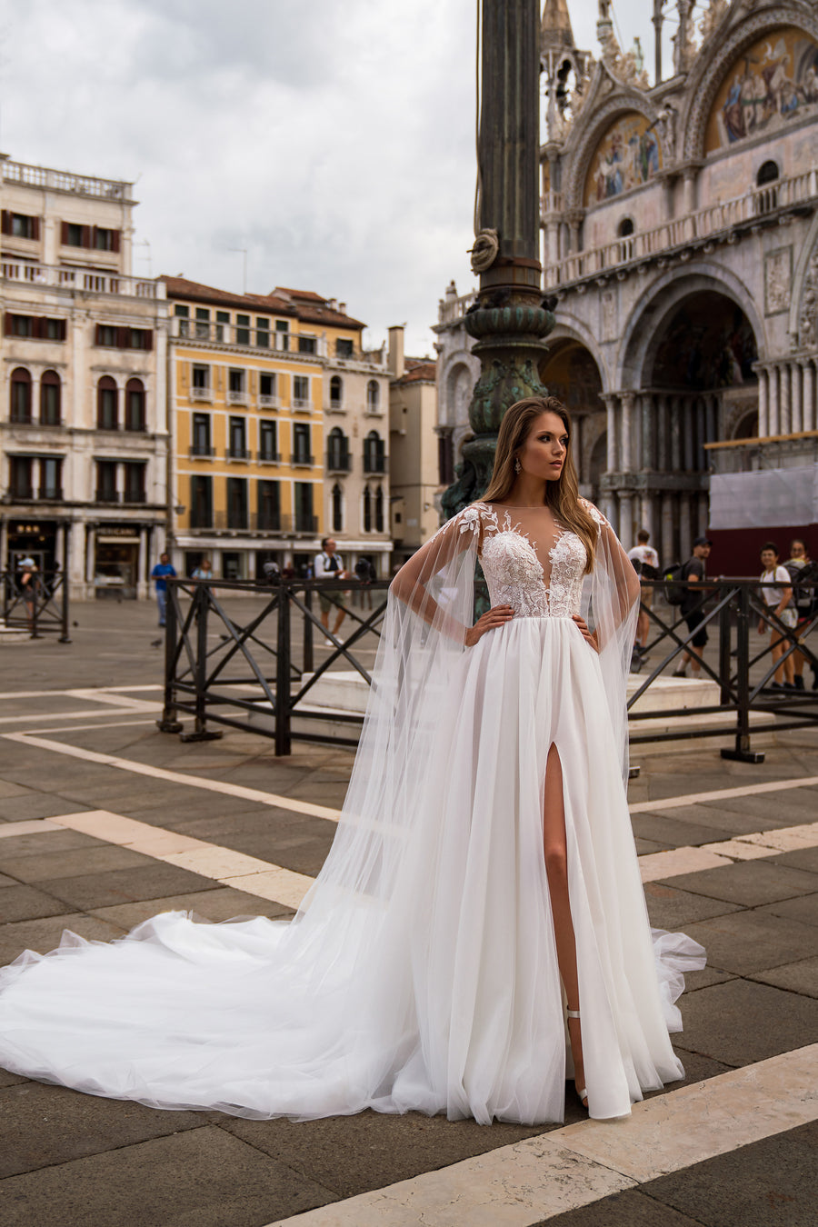 Ivory A-line wedding dress with floral lace bodice, sheer sleeves, deep V-neckline, slit, and train