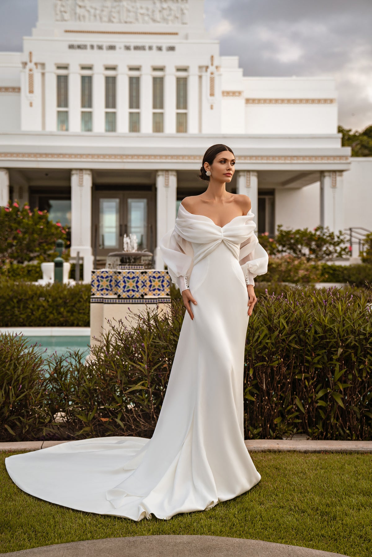 Ivory mermaid wedding dress with a draped off-the-shoulder bolero, twist-front bodice, fitted skirt, and long train