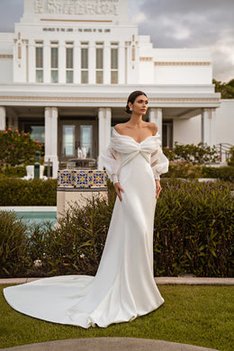 Ivory mermaid wedding dress with a draped off-the-shoulder bolero, twist-front bodice, fitted skirt, and long train