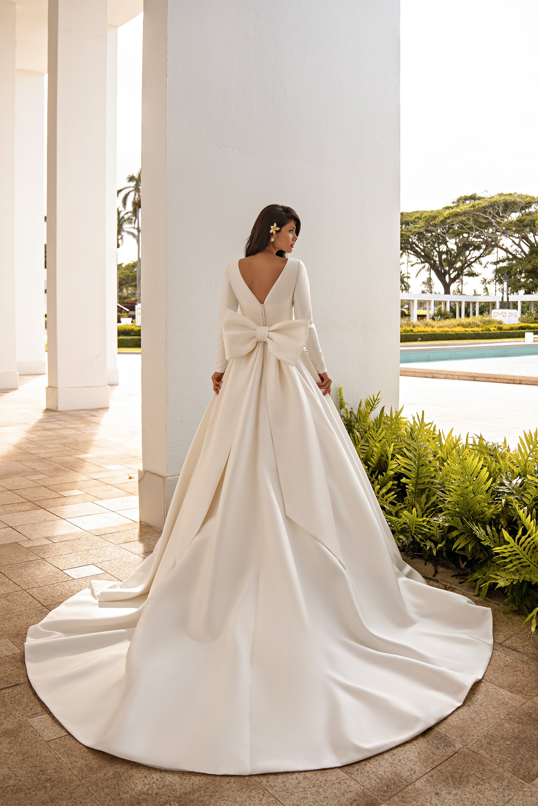 Ivory wedding dress with long sleeves, a large back bow, and a wide sweeping train