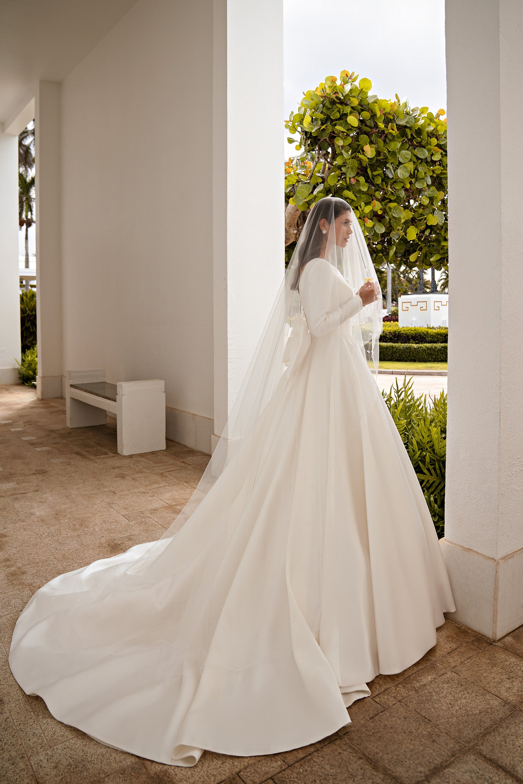 Side view of an ivory A-line wedding dress with long sleeves and a flowing train