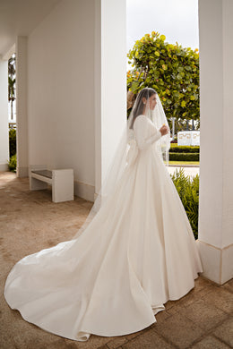Side view of an ivory A-line wedding dress with long sleeves and a flowing train