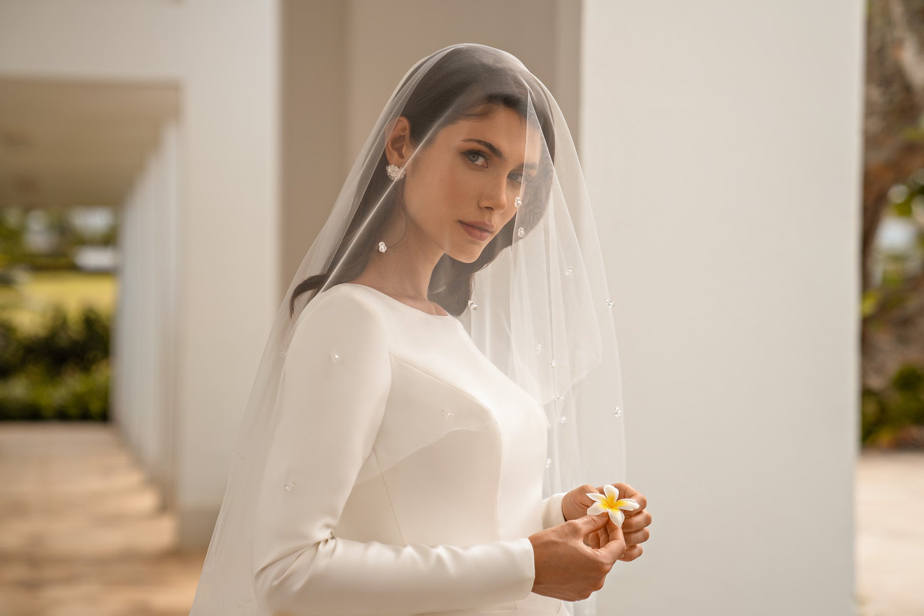 Close-up of an ivory wedding dress with a bateau neckline, long sleeves, and a fitted bodice