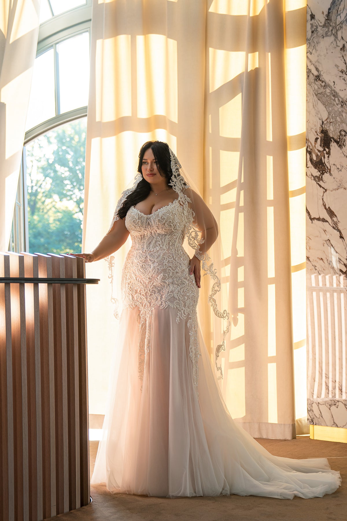 Ivory mermaid wedding dress with a plunging neckline, ornate lace bodice, sheer sleeves, and front slit