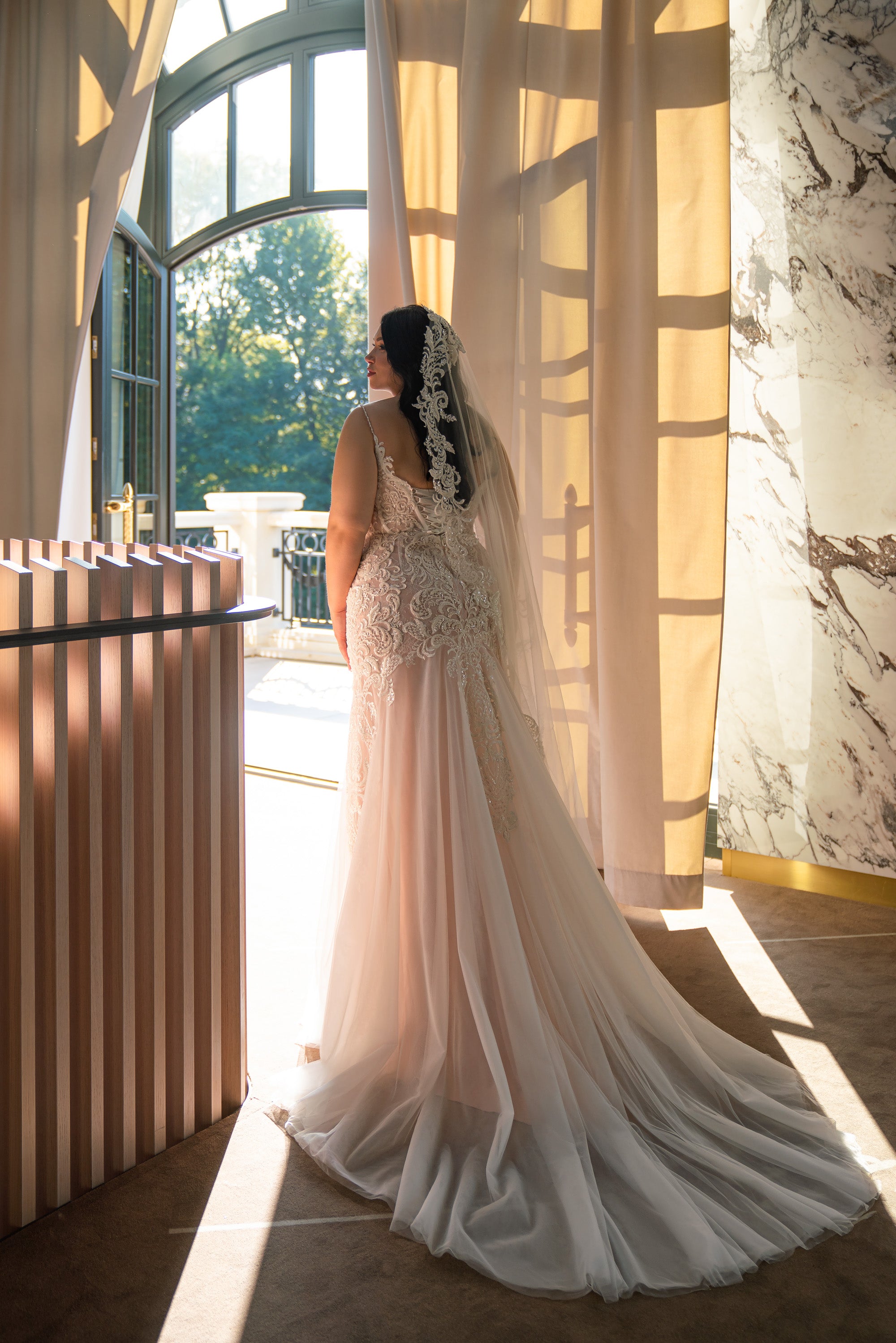 Open-back ivory wedding dress with an embellished lace bodice and long flowing mermaid train