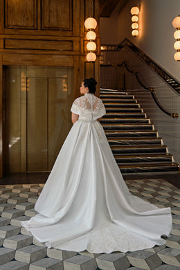 Lace-backed ball gown wedding dress with short sleeves, a full skirt, and a long flowing train