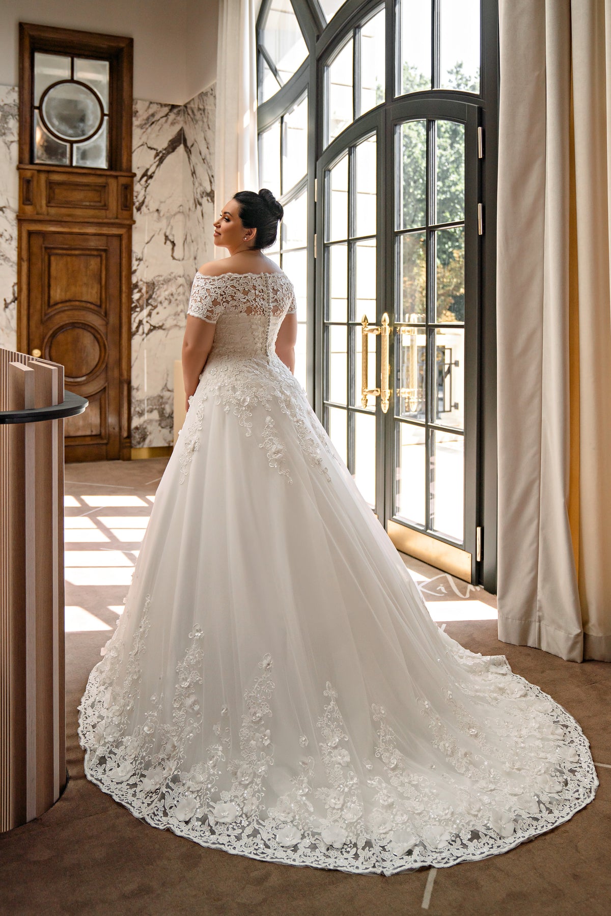 Lace-back ivory wedding dress with floral appliqués, a full ball-gown skirt, and a scalloped sweeping train