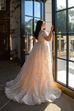 Beaded champagne wedding dress with an off-the-shoulder neckline, fitted silhouette, and long scalloped train
