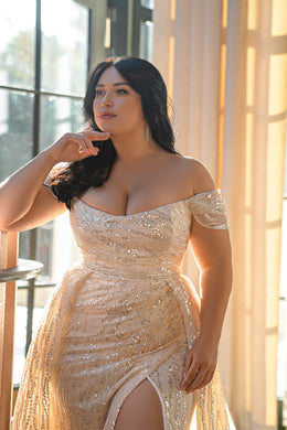 Close-up of a wedding dress with an off-the-shoulder neckline, draped beading, and thigh-high slit