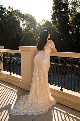 Rear view of a champagne beaded wedding dress with an off-the-shoulder neckline and floor-length train