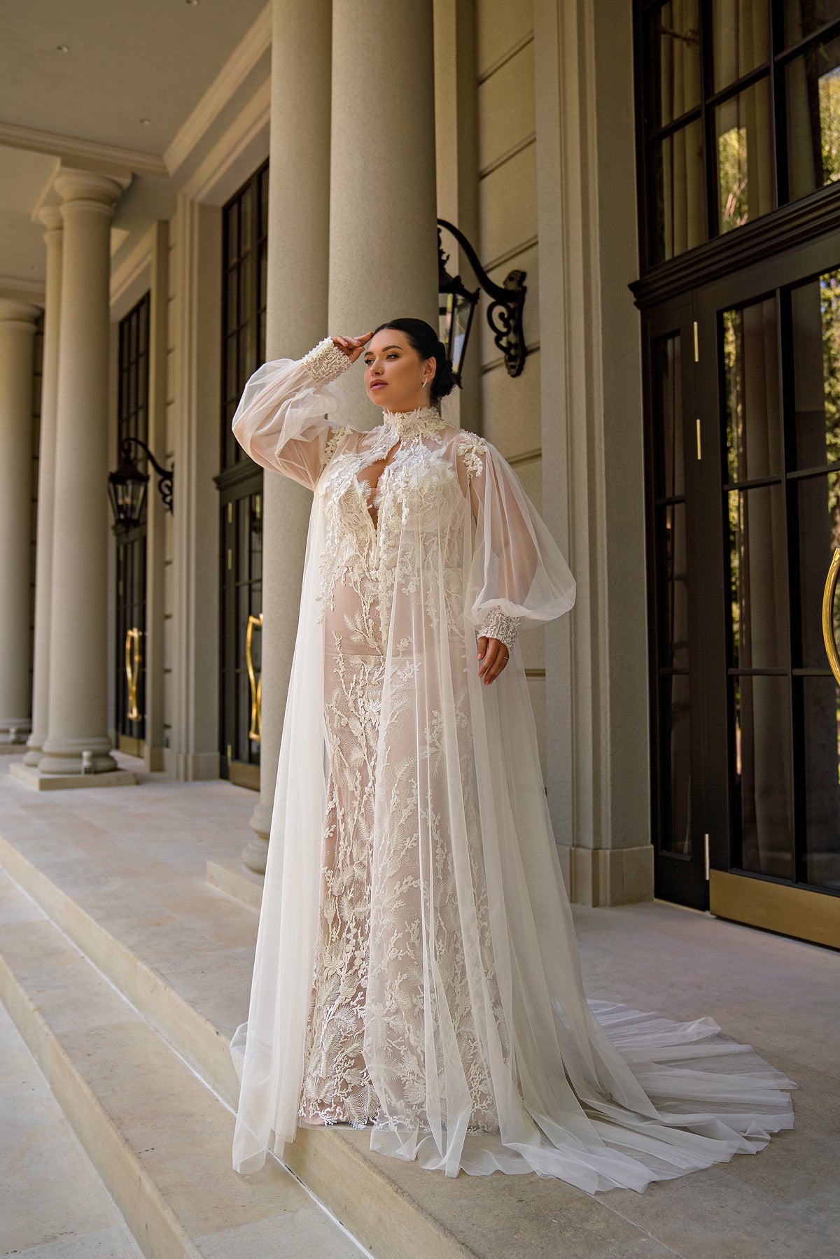 Ivory mermaid wedding dress with floral lace and a draped sheer tulle cape over the shoulders