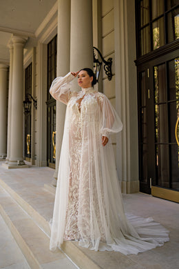 Ivory mermaid wedding dress with floral lace and a draped sheer tulle cape over the shoulders
