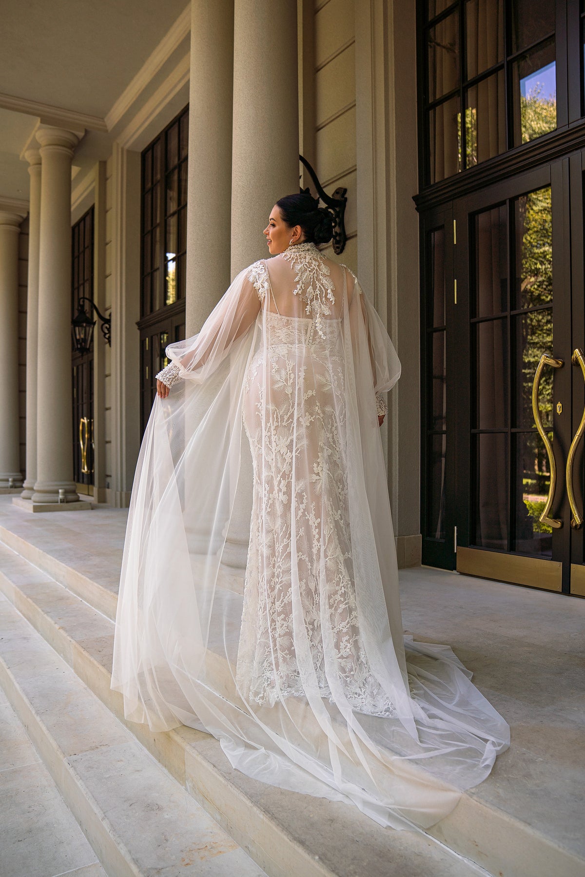 Lace-back ivory wedding dress shown with a detachable sheer tulle cape and long flowing train