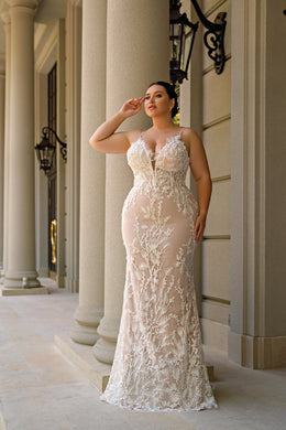 Ivory mermaid wedding dress with a plunging V-neckline, sheer straps, and floral lace overlay