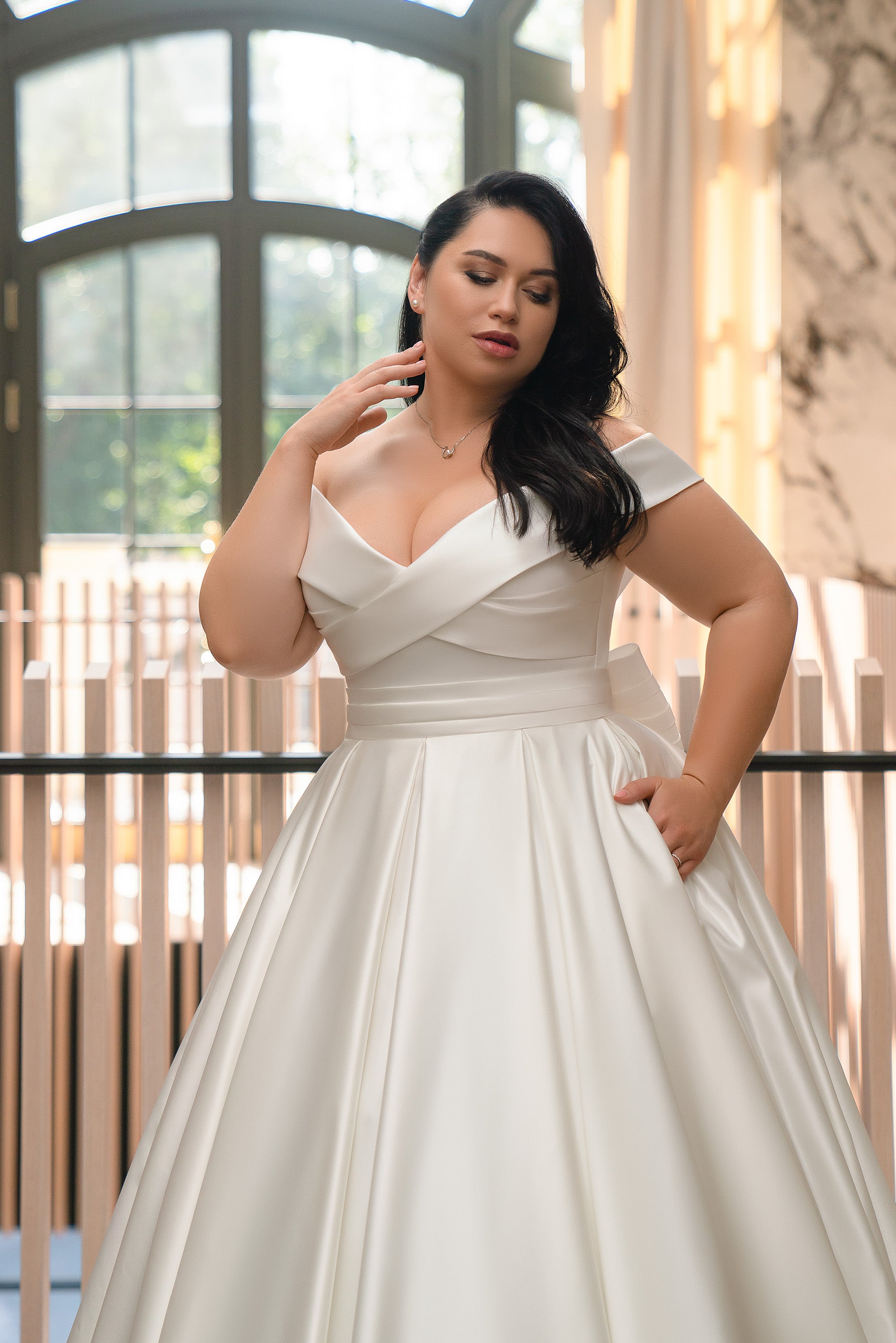 Ivory satin A-line wedding dress with an off-the-shoulder neckline and pleated wrap bodice