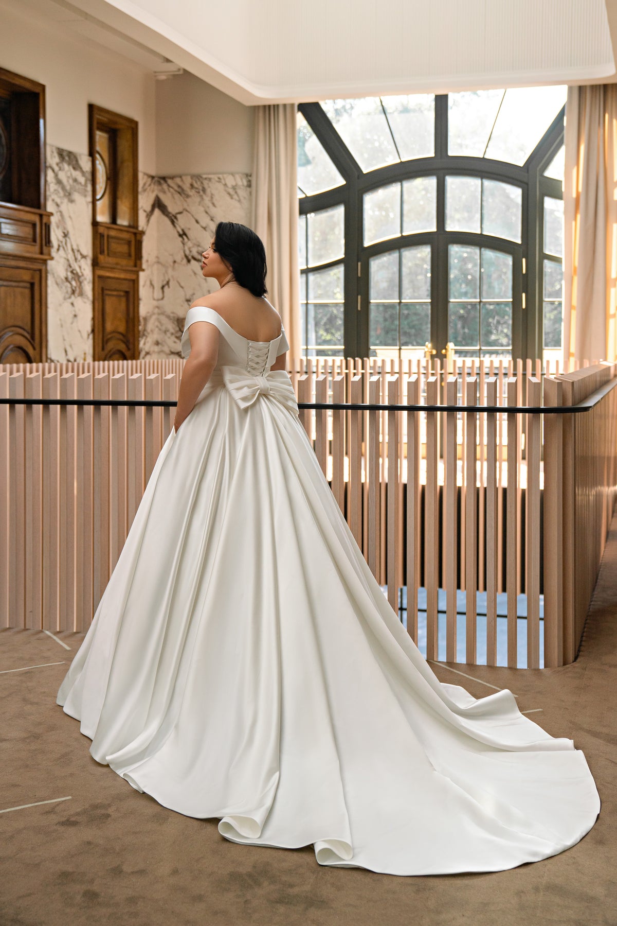 Ivory wedding dress with a lace-up corset back, waist bow, full A-line skirt, and sweeping train