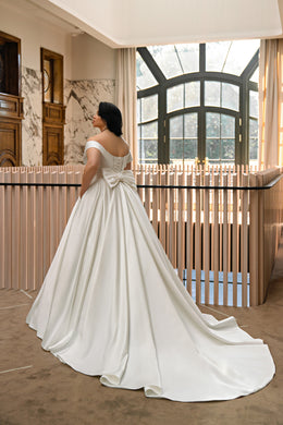 Ivory wedding dress with a lace-up corset back, waist bow, full A-line skirt, and sweeping train