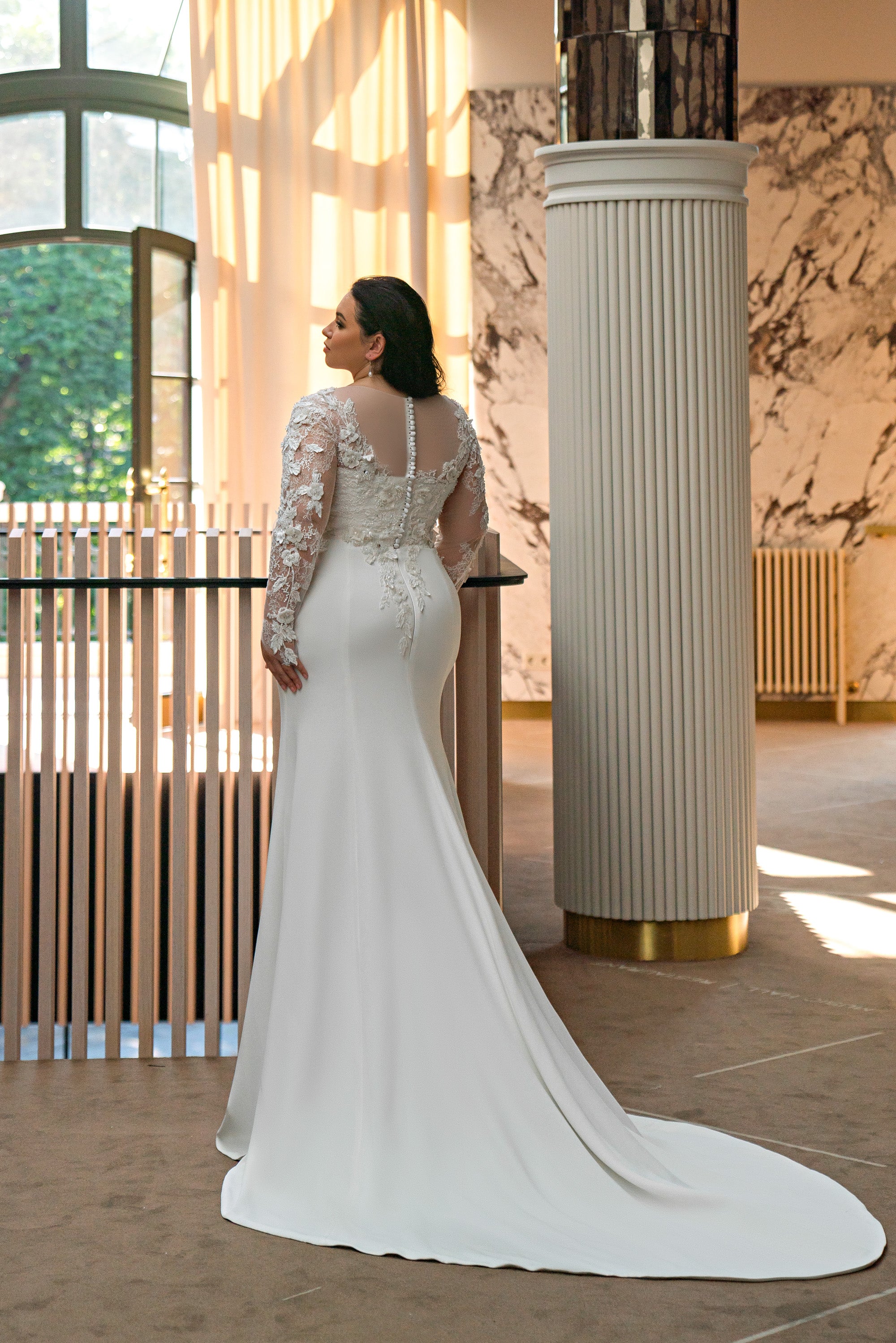 Ivory wedding dress with an illusion lace back, long lace sleeves, fitted trumpet skirt, and train