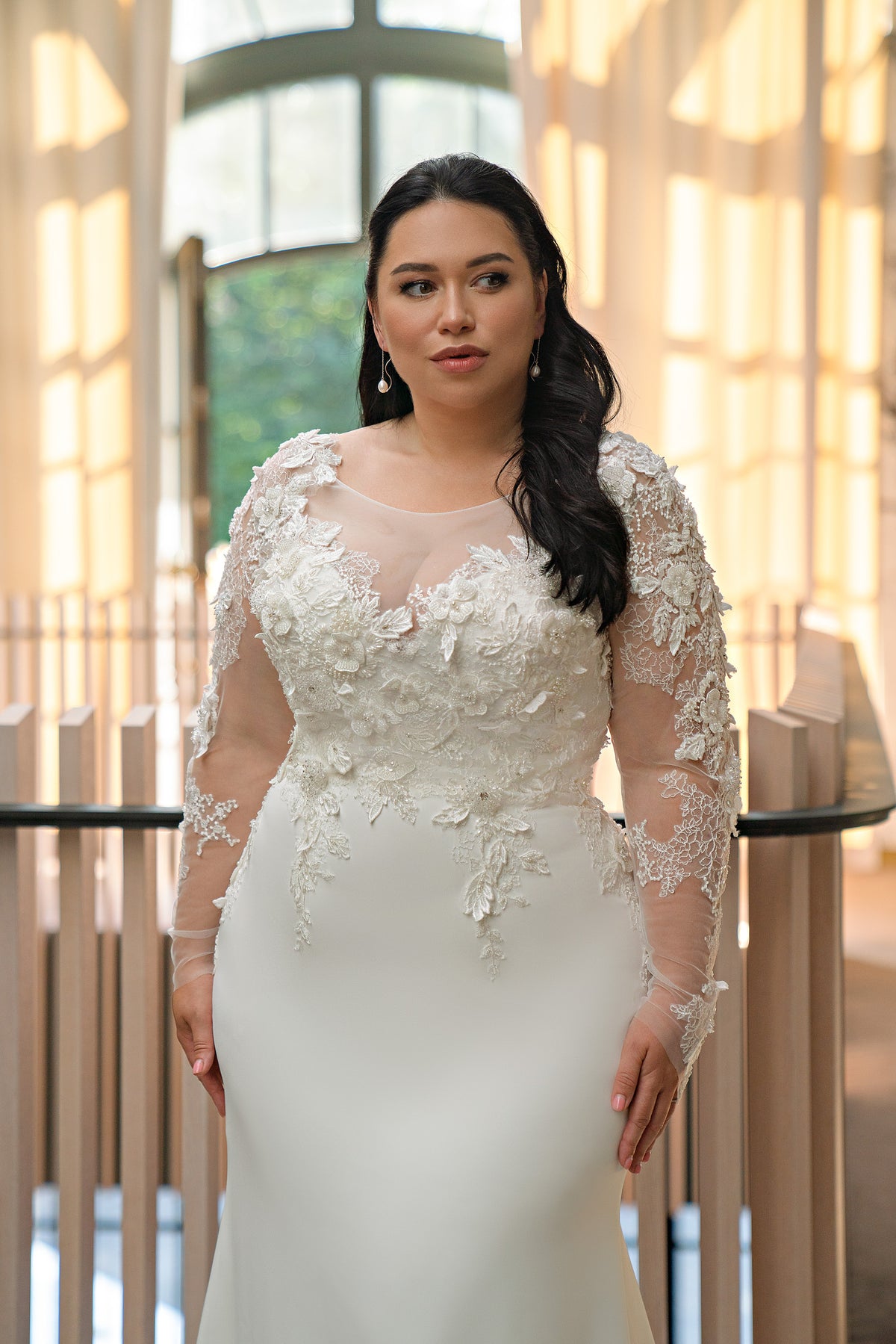 Close-up of floral lace appliqués, sheer neckline, and illusion sleeves on an ivory wedding dress
