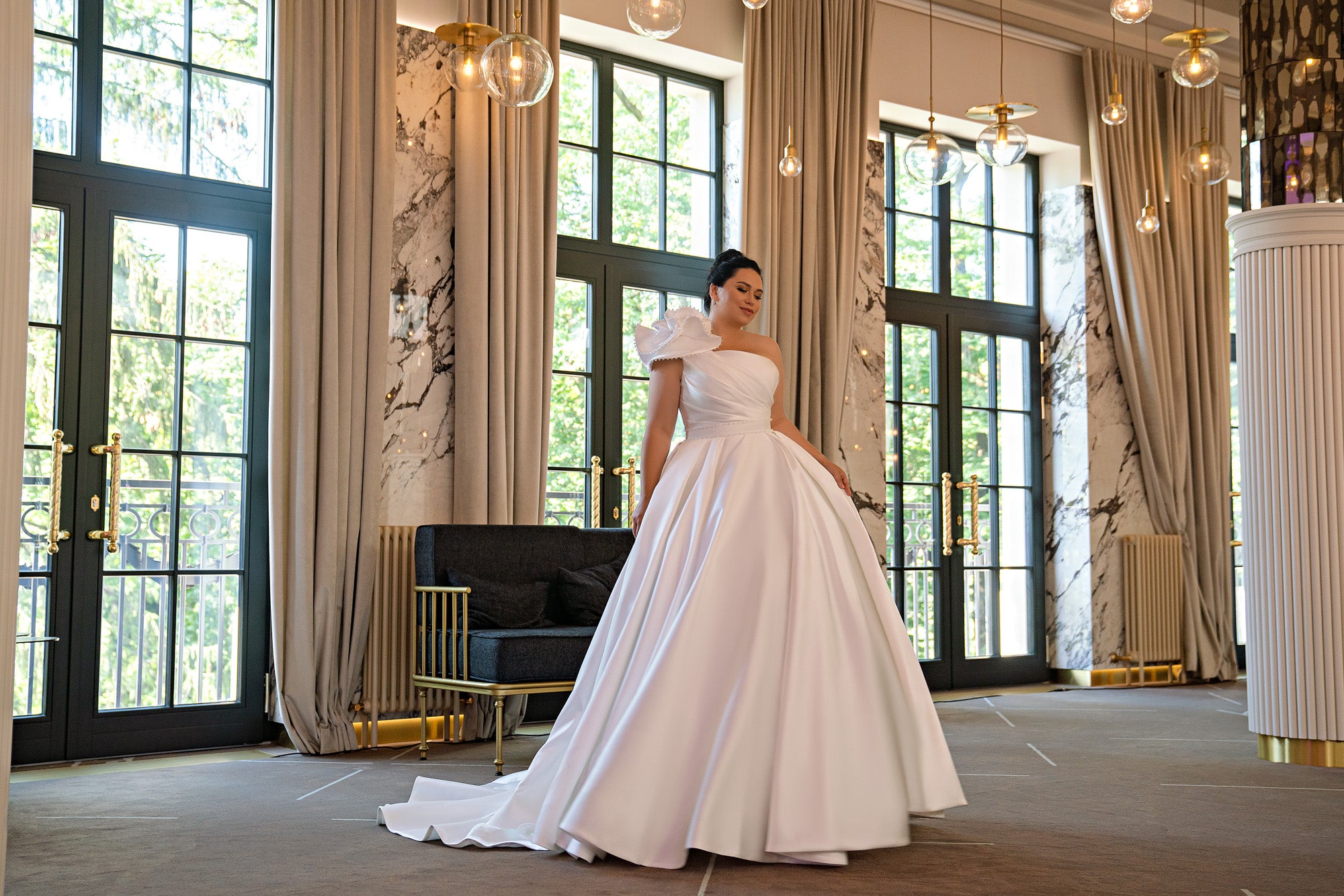 Ivory one-shoulder wedding dress with a full satin ball-gown skirt, sculpted waist, and trailing train