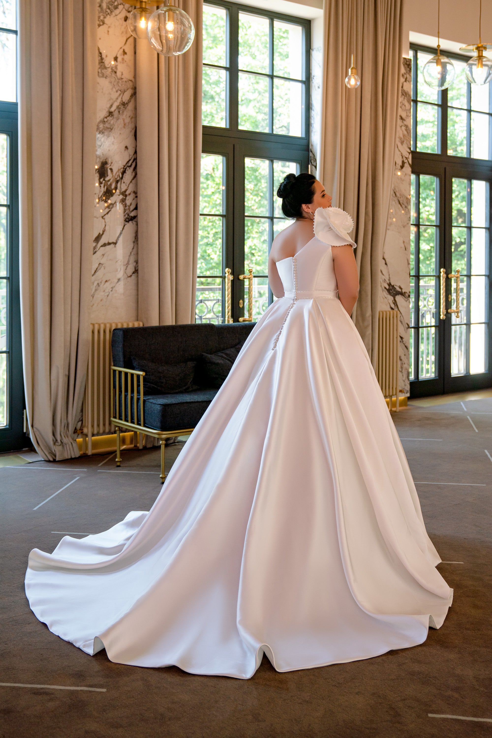 Ivory wedding dress with a fitted bodice, open back, ruffled shoulder detail, and sweeping satin ball-gown train